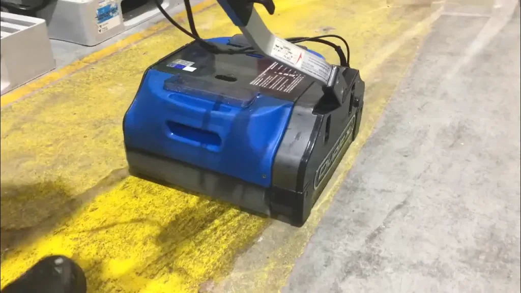 Industrial-grade floor scrubber removing grime from concrete floor inside a large warehouse.