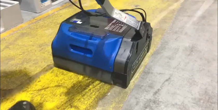 Industrial-grade floor scrubber removing grime from concrete floor inside a large warehouse.