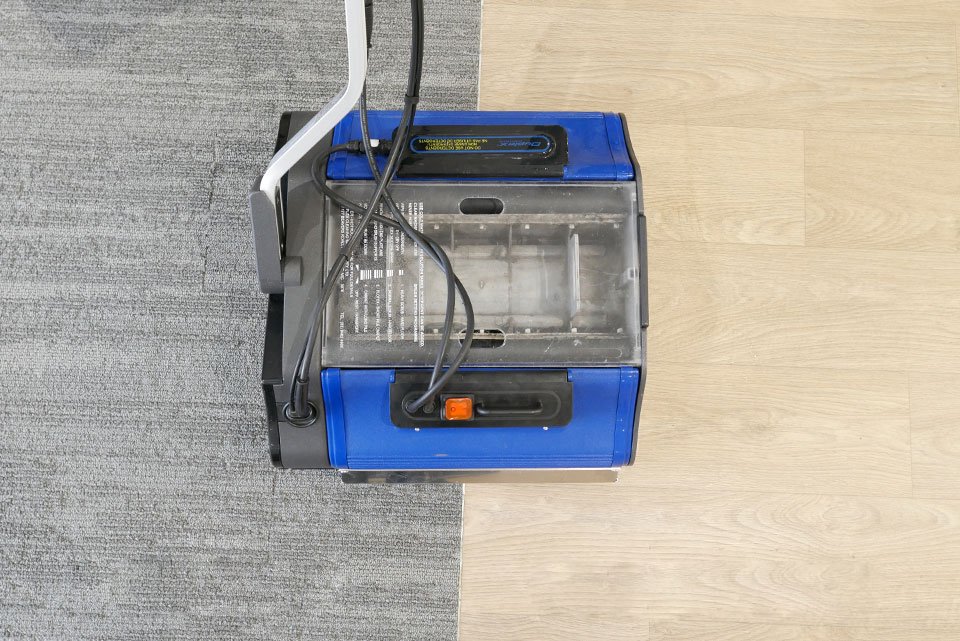 All-purpose floor scrubber machine in action on hard flooring and grey carpet, capturing mid-cleaning results.